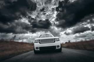 White Car Speed Driving On Road At Dramatic Clouds Daytime Wall Mural