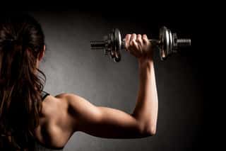 Atractive Fit Woman Works Out With Dumbbells As A Fitness Conceptual Over Dark Background Wall Mural