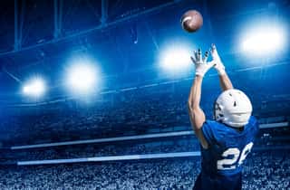 American Football Player Catching A Touchdown Pass In A Large Stadium  View From Below Wall Mural