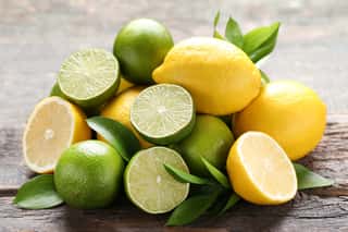 Lemons And Limes With Green Leafs On Grey Wooden Table Wall Mural