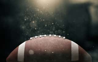 American Football Ball On Black Background Illuminated By The Wall Mural