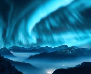Aurora Borealis Above The Mountains In Fog At Night  Northern Lights  Sky With Stars With Polar Lights And High Rocks  Beautiful Landscape With Aurora, City Lights In Low Clouds, Mountain Peaks  Space Wall Mural
