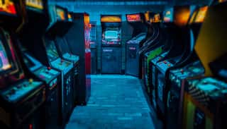 Arcade Video Games In An Empty Dark Gaming Room With Purple Light With Glowing Vintage Displays And Beautiful Old Retro Design Wall Mural