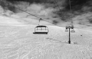 Black And White Snowy Off-piste Ski Slope, Chair-lift On Ski Resort And Sky With Clouds Wall Mural