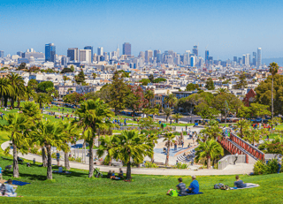 Panoramic View Of Local People Enjoying The Sunny Summer Weather At Mission Dolores Park On A Beautiful Day With Clear Blue Sky With The Skyline Of San Francisco In The Background, California, USA Wall Mural