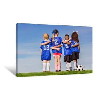 Image of Diverse Group Of Boys And Girls Soccer Players Standing Together With A Ball Against A Simple Blue Sky Background Canvas Print