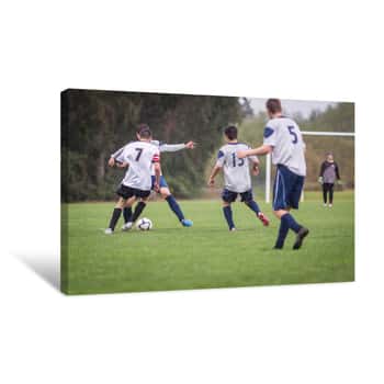 Image of Young Men Playing Soccer In The Rain On A Grass Field Canvas Print