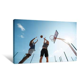 Image of Low Angle  Of Two Young Men Playing Basketball And Jumping By Hoop Against Blue Sky, Copy Space Canvas Print