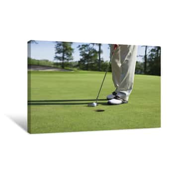 Image of Golfer Taps In With Putter On Green With Trees Near A Lake Canvas Print