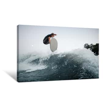 Image of Young And Active Wakeboarder Jumping On The Blue Splashing Wave Against The Background Of Clear Sky On The Foreground Canvas Print